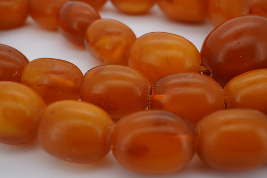 A single strand graduated oval amber bead necklace, 66cm, gross weight 63 grams. Condition - poor to fair